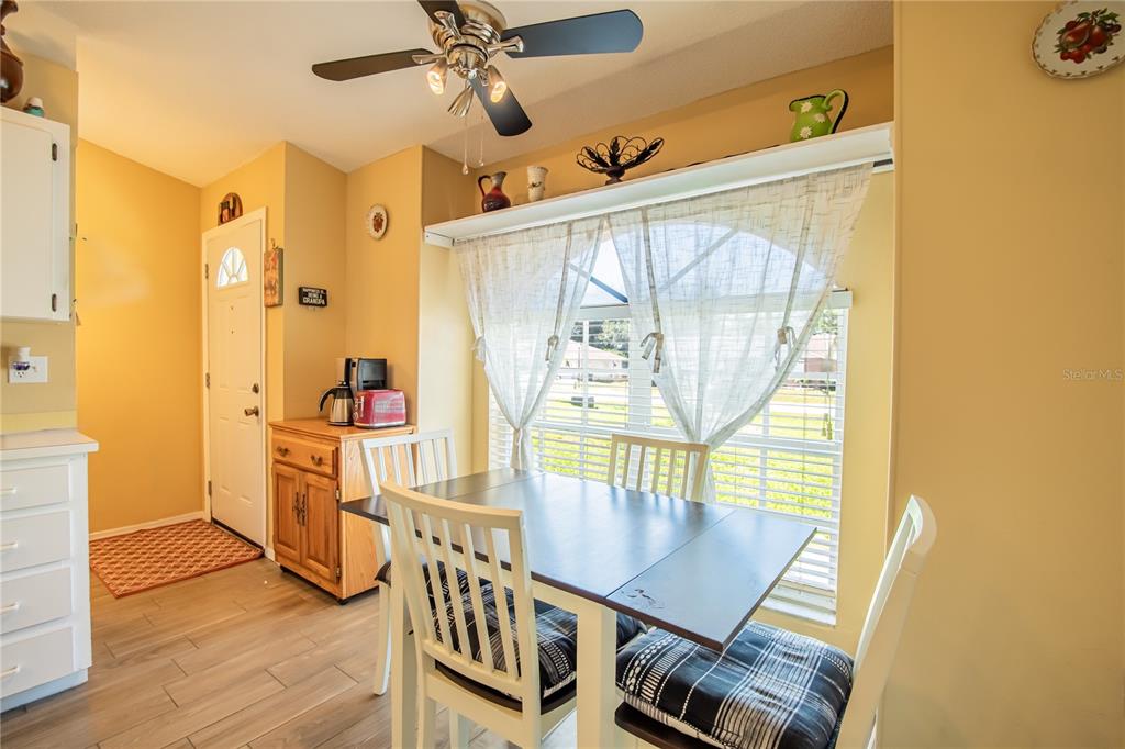 A dining area features a wooden table, white chairs, a ceiling fan, and a window — 7212 PEBBLE PASS LOOP, LAKELAND, FL