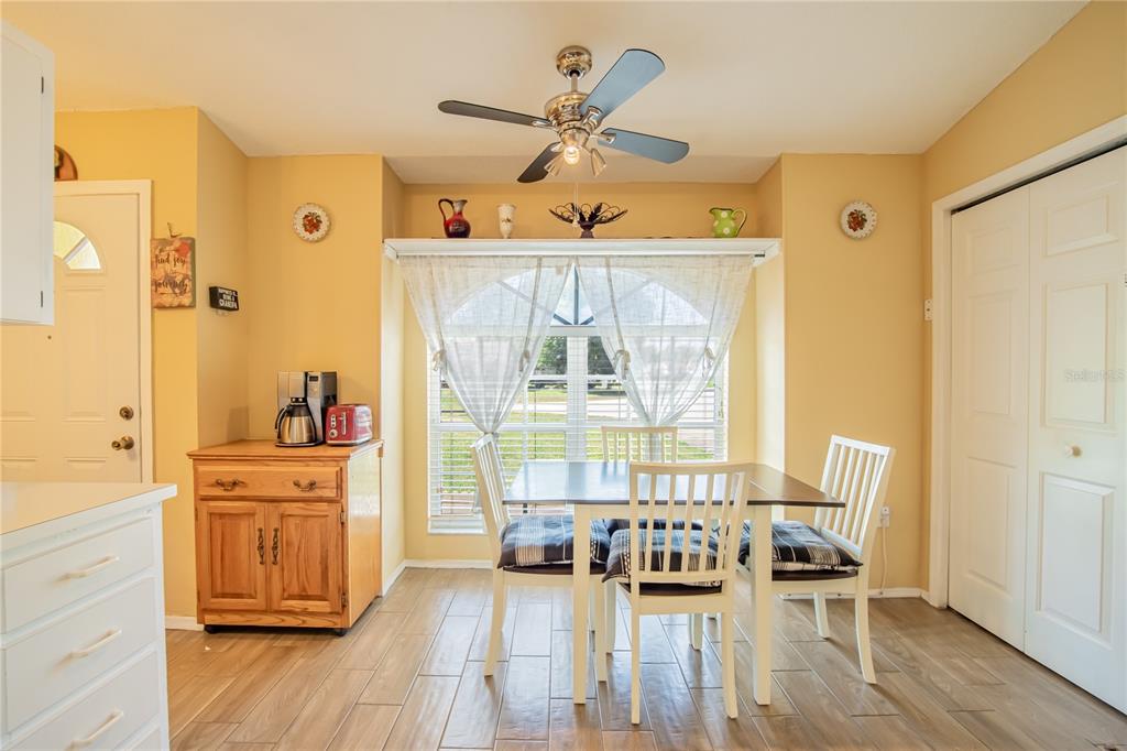 A dining area with yellow walls, a ceiling fan, a window, and a wooden cabinet — 7212 PEBBLE PASS LOOP, LAKELAND, FL
