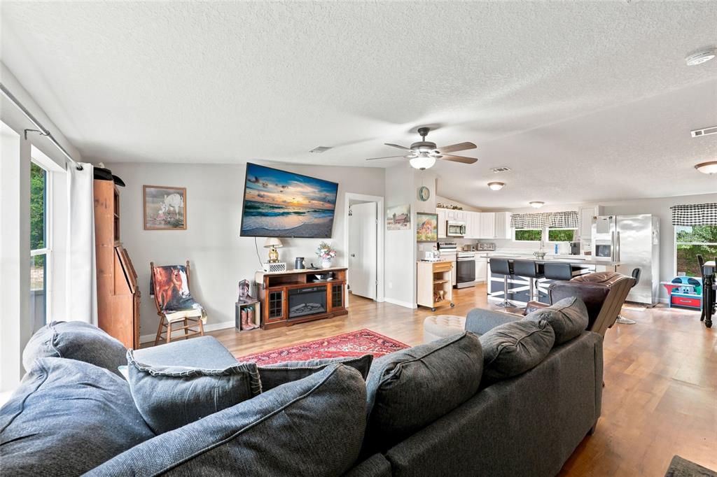 An open-concept living room and kitchen featuring a gray sectional sofa and wood flooring — 3562 NW 20TH AVENUE, BELL, FL