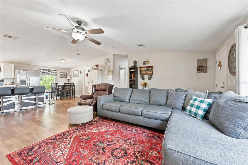 A living room with a gray sectional, red patterned rug, and an open-concept kitchen — 3562 NW 20TH AVENUE, BELL, FL