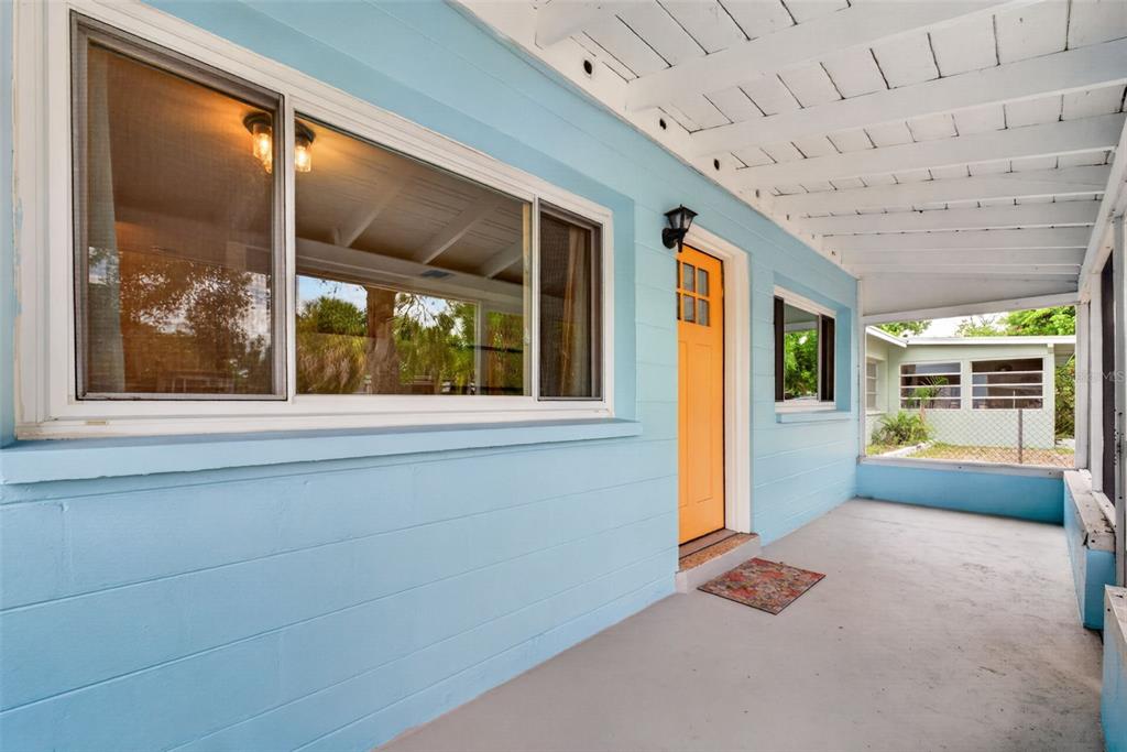 A covered porch with light blue walls, a bright orange door, and a concrete floor — 5400 97TH TERRACE N, PINELLAS PARK, FL