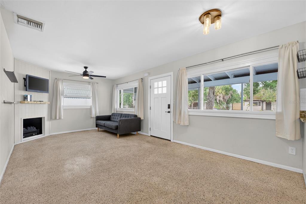 A living room features beige carpeting, a fireplace, a gray sofa, and a ceiling fan — 5400 97TH TERRACE N, PINELLAS PARK, FL