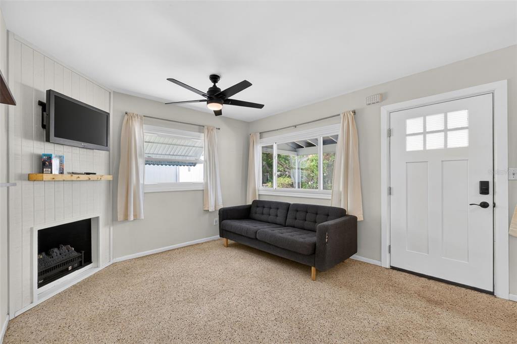 A living room features a fireplace, a dark gray sofa, and a white front door — 5400 97TH TERRACE N, PINELLAS PARK, FL