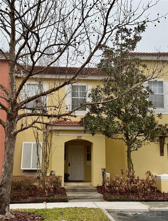 A two-story yellow townhouse with a covered entryway and a white front door — 157 POMPANO BEACH DRIVE, KISSIMMEE, FL