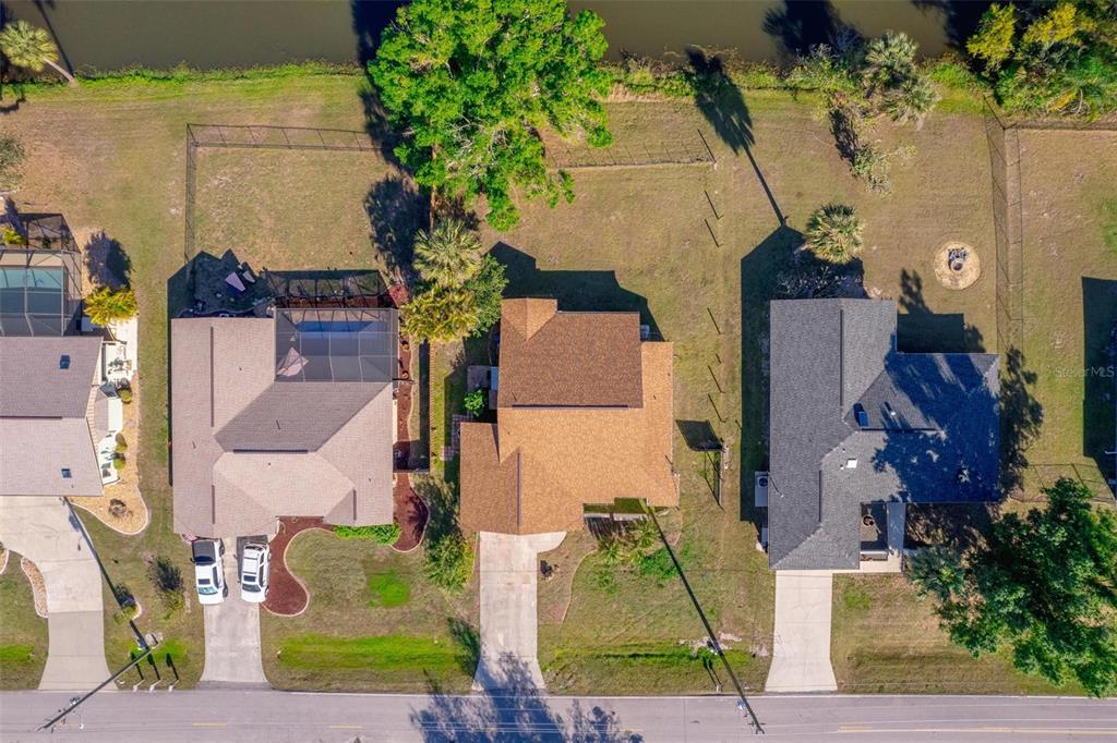 An aerial view shows three suburban houses with driveways and backyards bordering a small lake — 1224 INVERNESS STREET, PORT CHARLOTTE, FL