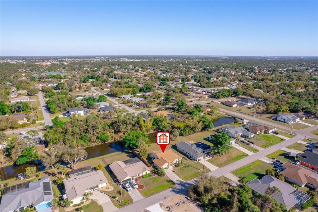 An aerial view shows a suburban house with a brown roof and a backyard pond — 1224 INVERNESS STREET, PORT CHARLOTTE, FL