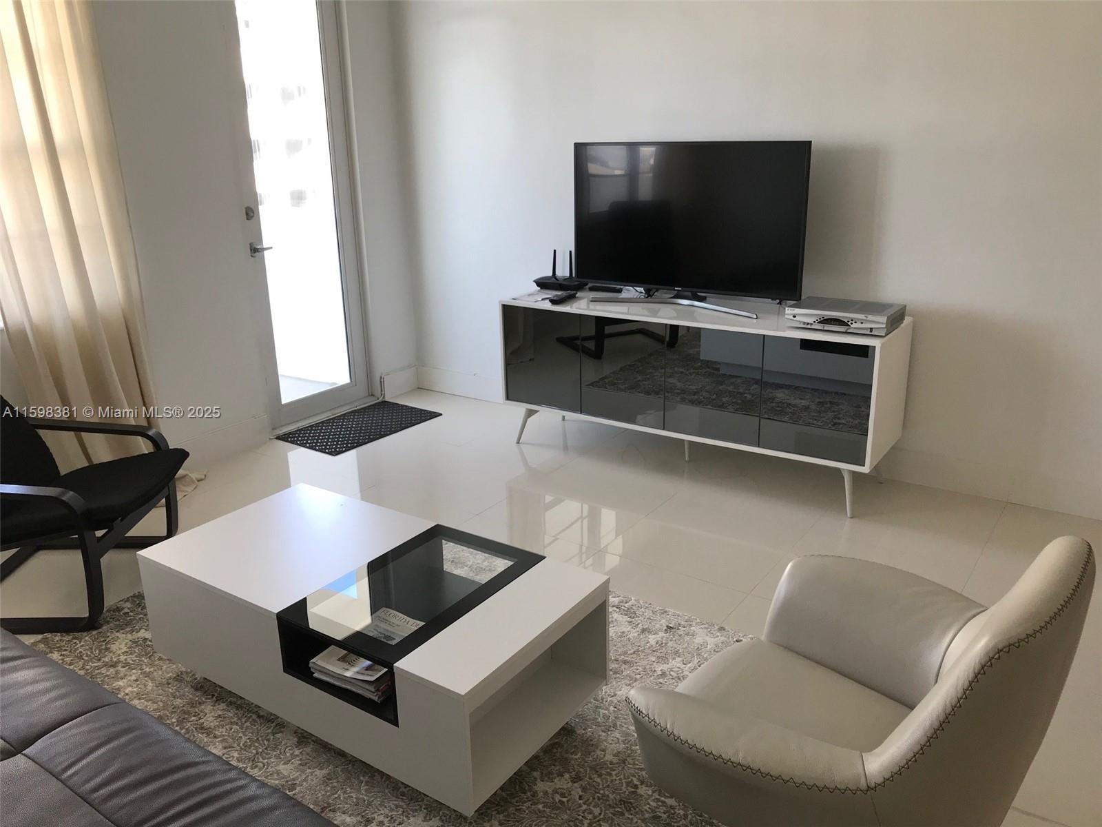 A living room features a white media console, a modern coffee table, and two chairs — 100 Lincoln Rd # 808, Miami Beach FL 33139, MIAMI BEACH, FL