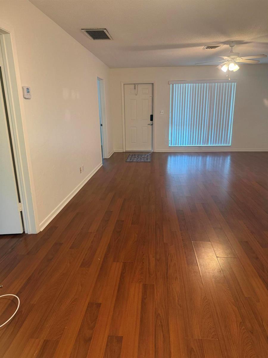 A living room features wood-look flooring, a white front door, and a ceiling fan — 1151 NE 26th Avenue, Pompano Beach FL 33062, POMPANO BEACH, FL