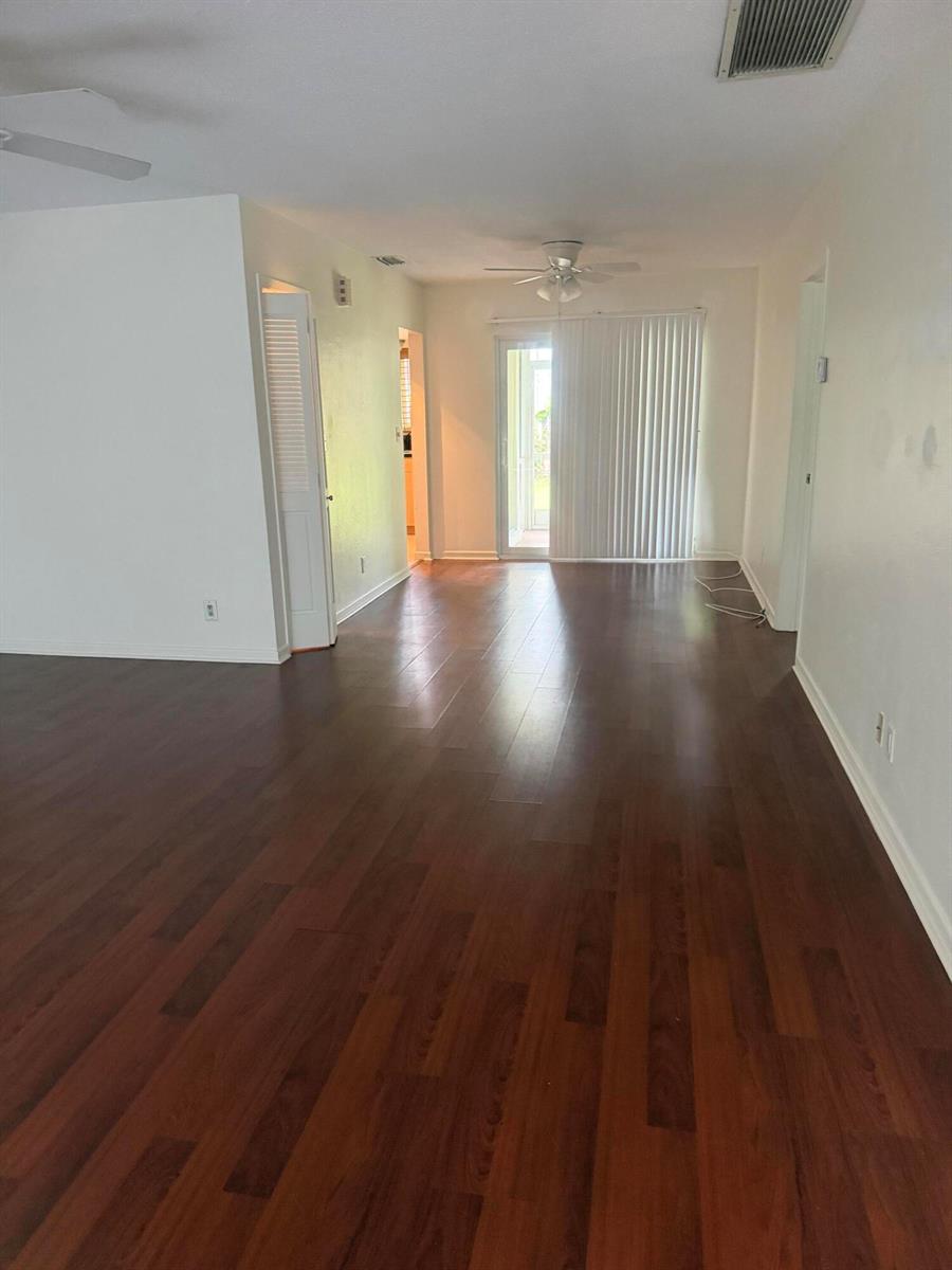 An empty living room features dark wood flooring, white walls, and a sliding glass door — 1151 NE 26th Avenue, Pompano Beach FL 33062, POMPANO BEACH, FL