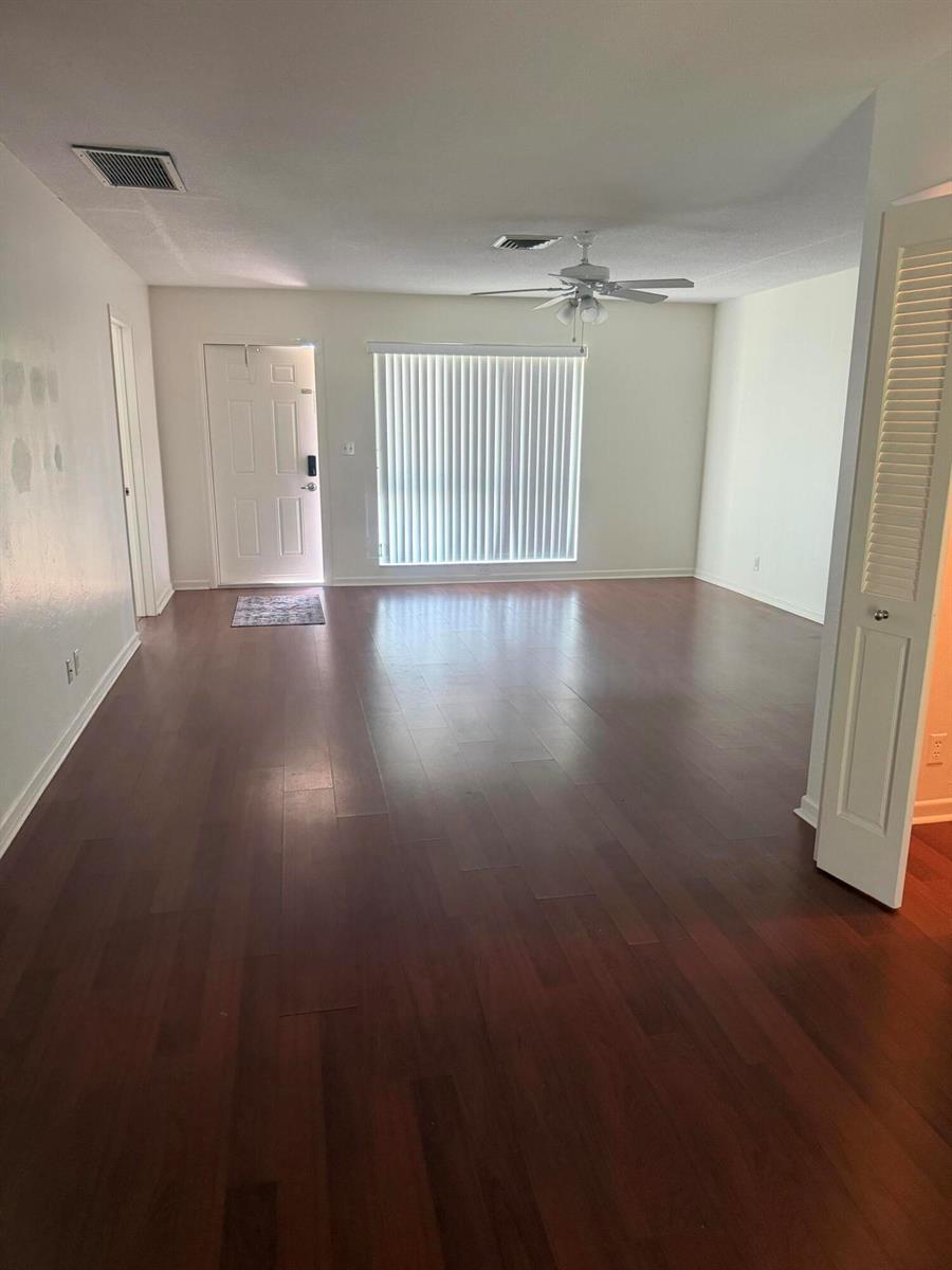 An empty living room features dark wood-look flooring, white walls, and a ceiling fan — 1151 NE 26th Avenue, Pompano Beach FL 33062, POMPANO BEACH, FL