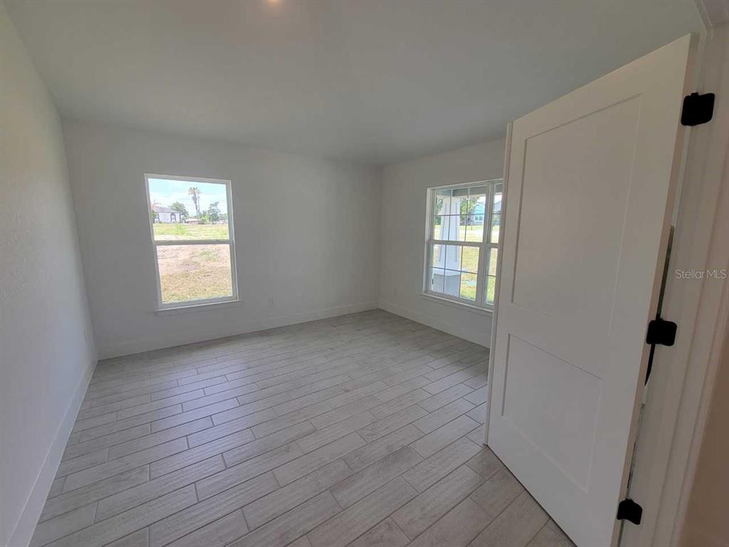 A bedroom with white walls, light wood-look tile flooring, and two windows — 4626 SW 103RD STREET ROAD, OCALA, FL