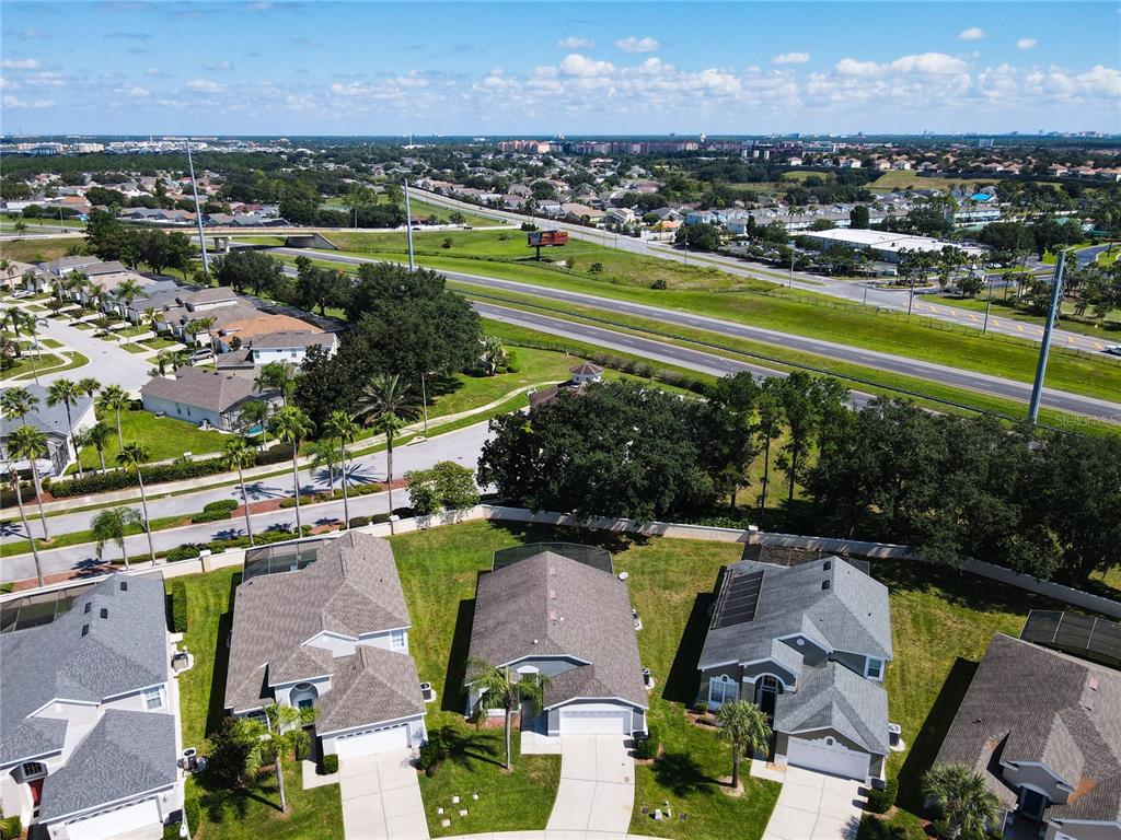 An aerial view shows several suburban houses with driveways near a highway and trees — 8050 KING PALM CIRCLE, KISSIMMEE, FL