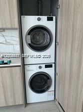 A stacked washer and dryer unit is installed inside a wooden cabinet in a kitchen — 77 SE 5th St # 312, Miami FL 33131, MIAMI, FL