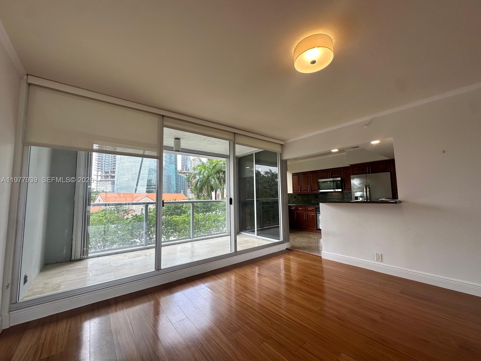 A living room with hardwood floors, a sliding glass door to a balcony, and kitchen — 1541 Brickell Ave # B403, Miami FL 33129, MIAMI, FL