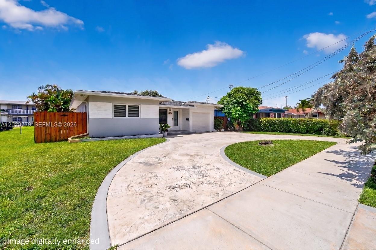 A single-story house with a white facade, a curved concrete driveway, and a wooden fence — 709 NW 9th Ct, Hallandale Beach FL 33009, HALLANDALE BEACH, FL