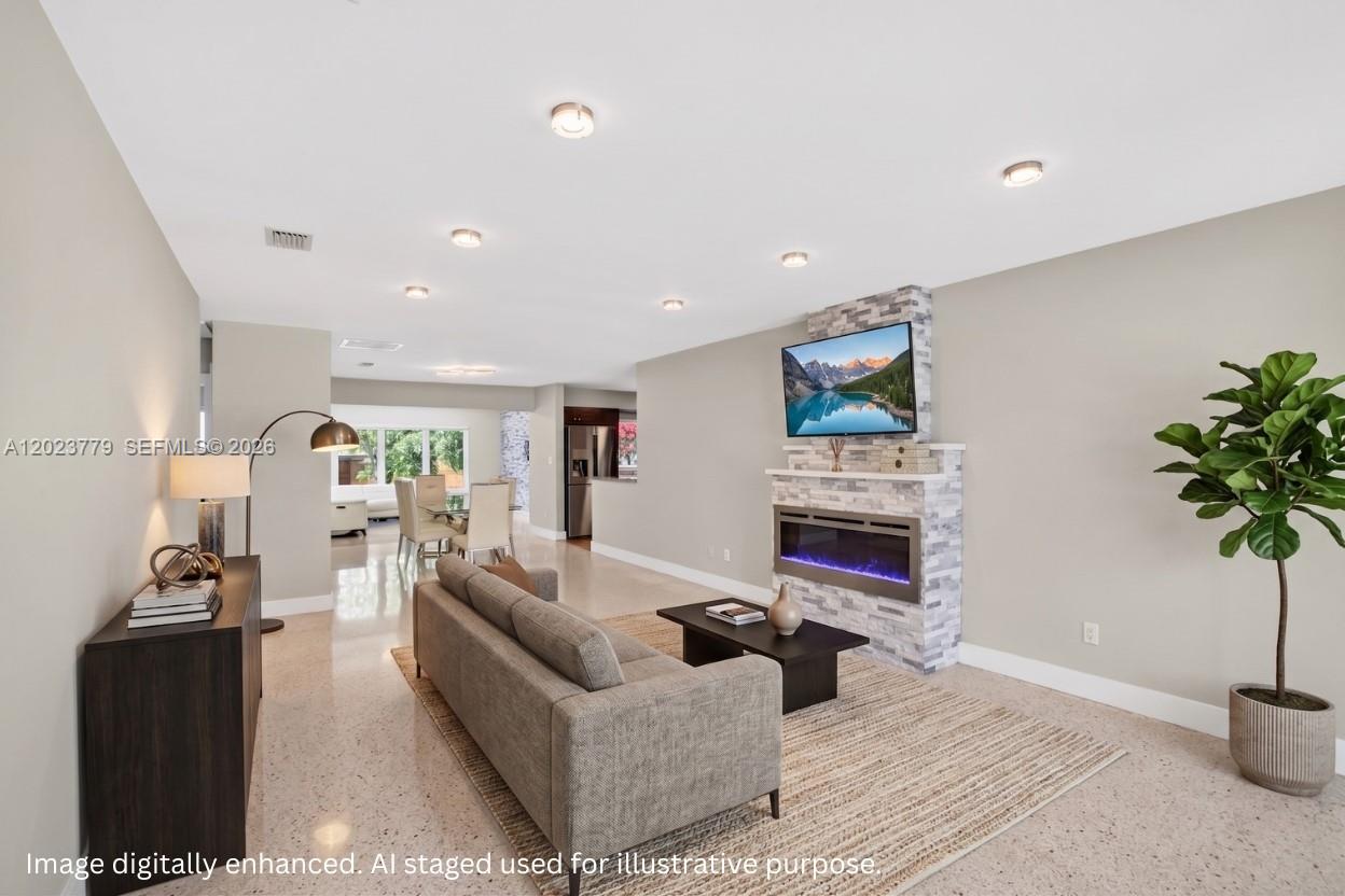 A living room features a stone fireplace, a gray sofa, and recessed ceiling lighting — 709 NW 9th Ct, Hallandale Beach FL 33009, HALLANDALE BEACH, FL