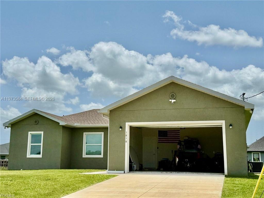 A single-story house with olive green stucco siding and an attached two-car garage — 1818 Inwood RD, La Belle FL 33935, LA BELLE, FL