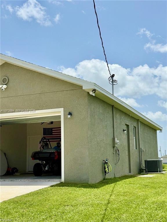 The exterior of a stucco house features an open garage containing an all-terrain vehicle — 1818 Inwood RD, La Belle FL 33935, LA BELLE, FL