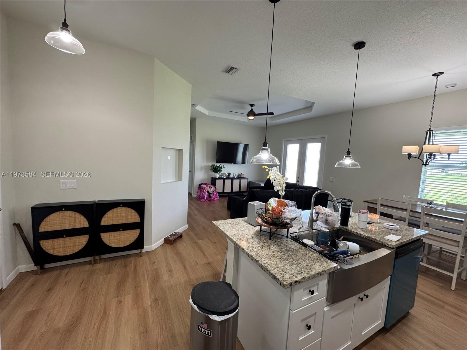 A kitchen with granite countertops and a farmhouse sink opens into a living area — 1818 Inwood RD, La Belle FL 33935, LA BELLE, FL