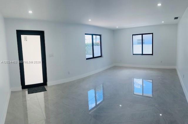 An empty room features light gray walls, large glossy floor tiles, and black-framed windows and doors — 11870 SW 5th # 1, Miami FL 33184, MIAMI, FL
