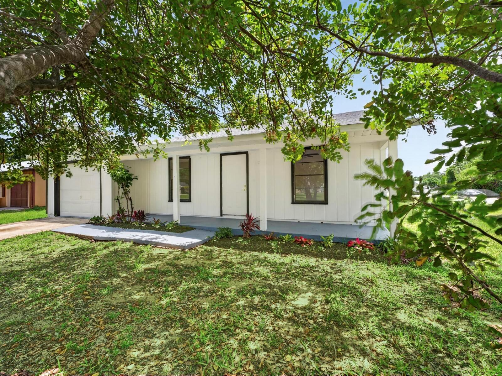 A white single-story house with a covered porch, dark window frames, and a garage — 2575 1st Place, Vero Beach FL 32962, VERO BEACH, FL