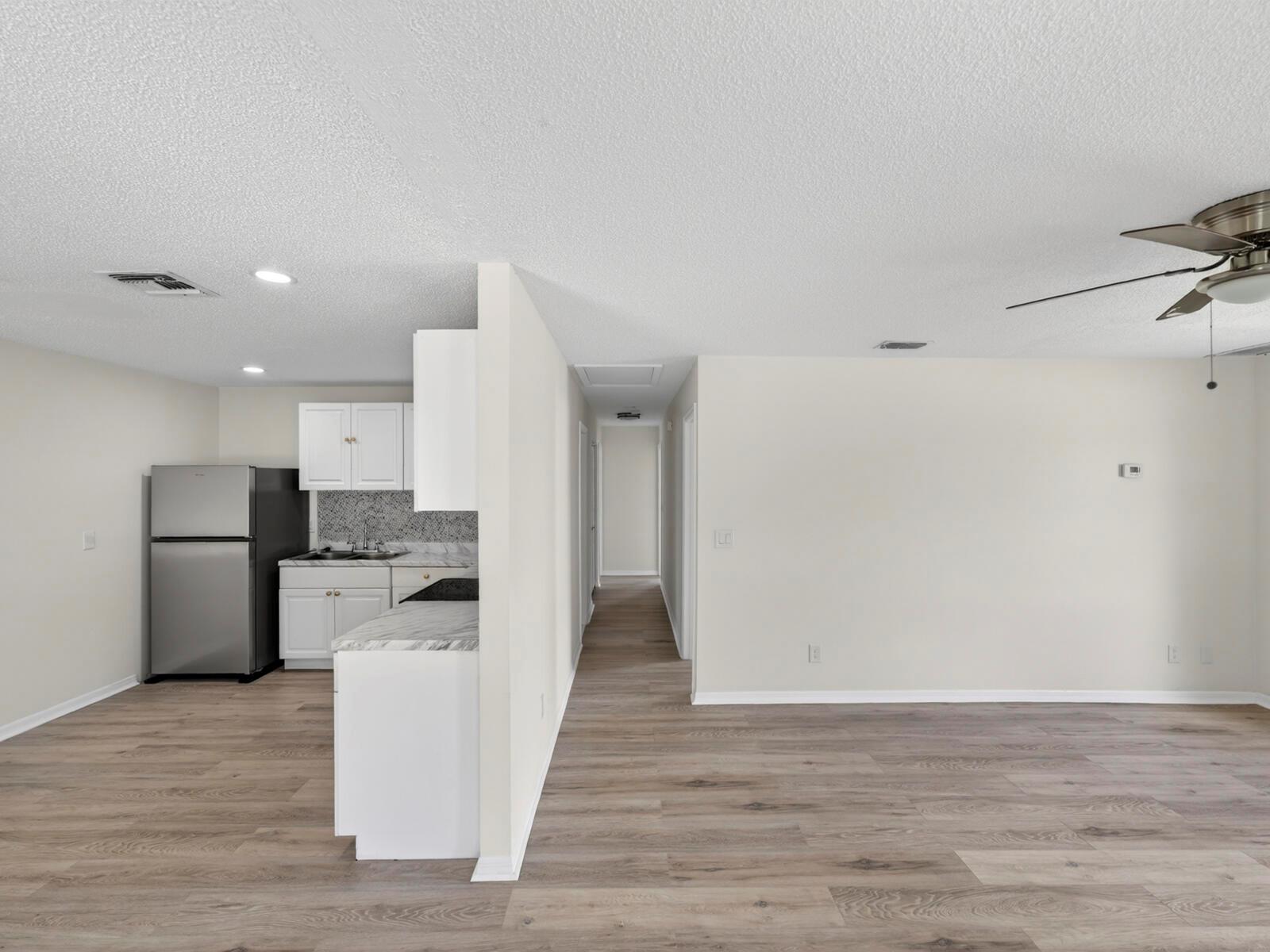 A kitchen with stainless steel appliances and white cabinets opens to a living area — 2575 1st Place, Vero Beach FL 32962, VERO BEACH, FL