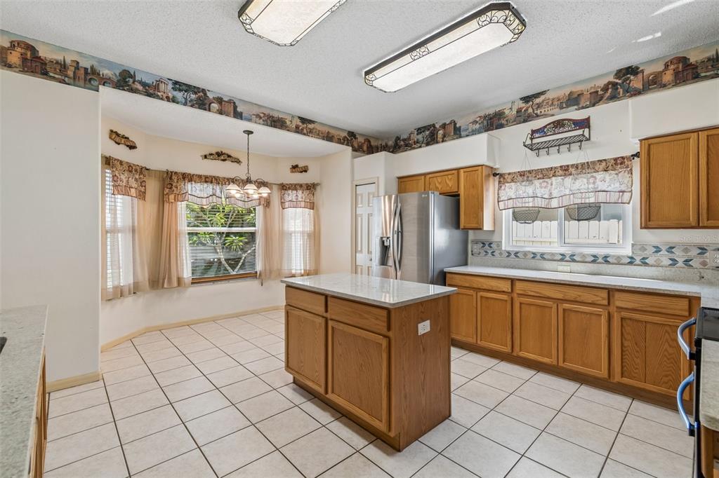 A kitchen with oak cabinets, a central island, tile flooring, and a breakfast nook area — 12803 LONGCREST DRIVE, RIVERVIEW, FL