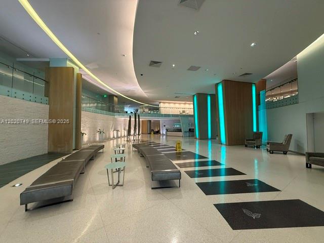 A modern, spacious lobby features long benches, recessed lighting, and illuminated teal accent pillars — 92 SW 3rd St # 1804, Miami FL 33130, MIAMI, FL