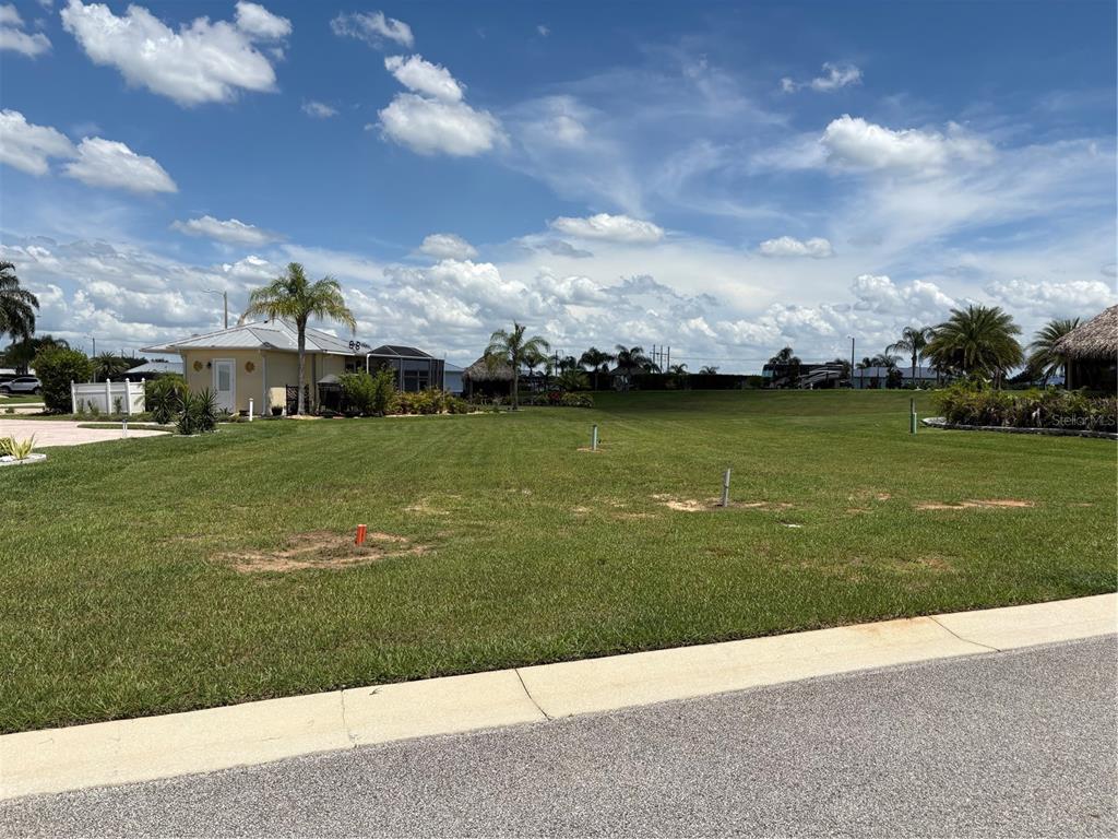 A grassy vacant lot sits next to a house under a cloudy blue sky — 2884 WOOD DUCK DRIVE, POLK CITY, FL
