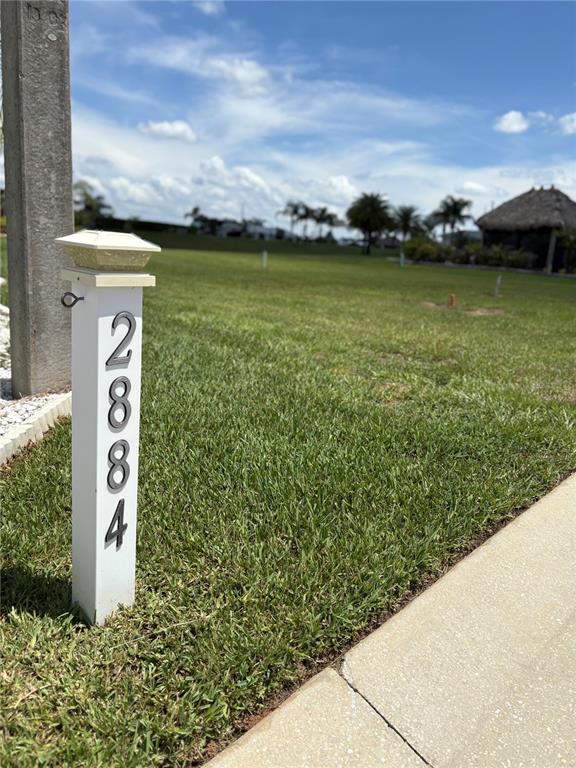 A white post with the house number 2884 stands on a grassy vacant lot — 2884 WOOD DUCK DRIVE, POLK CITY, FL
