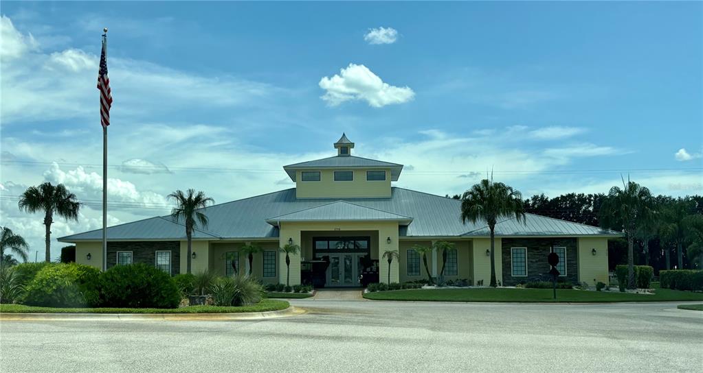 A yellow clubhouse with a metal roof, a central cupola, and an American flag — 2884 WOOD DUCK DRIVE, POLK CITY, FL