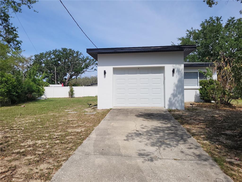 A white single-car garage with a concrete driveway sits on a grassy lot — 105 FOREST PARK AVENUE, TEMPLE TERRACE, FL
