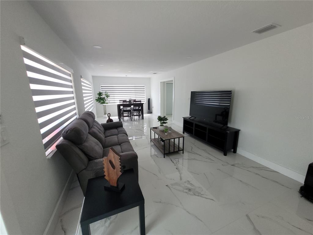 A living room features gray tile flooring, a gray sofa, a coffee table, and a television — 105 FOREST PARK AVENUE, TEMPLE TERRACE, FL