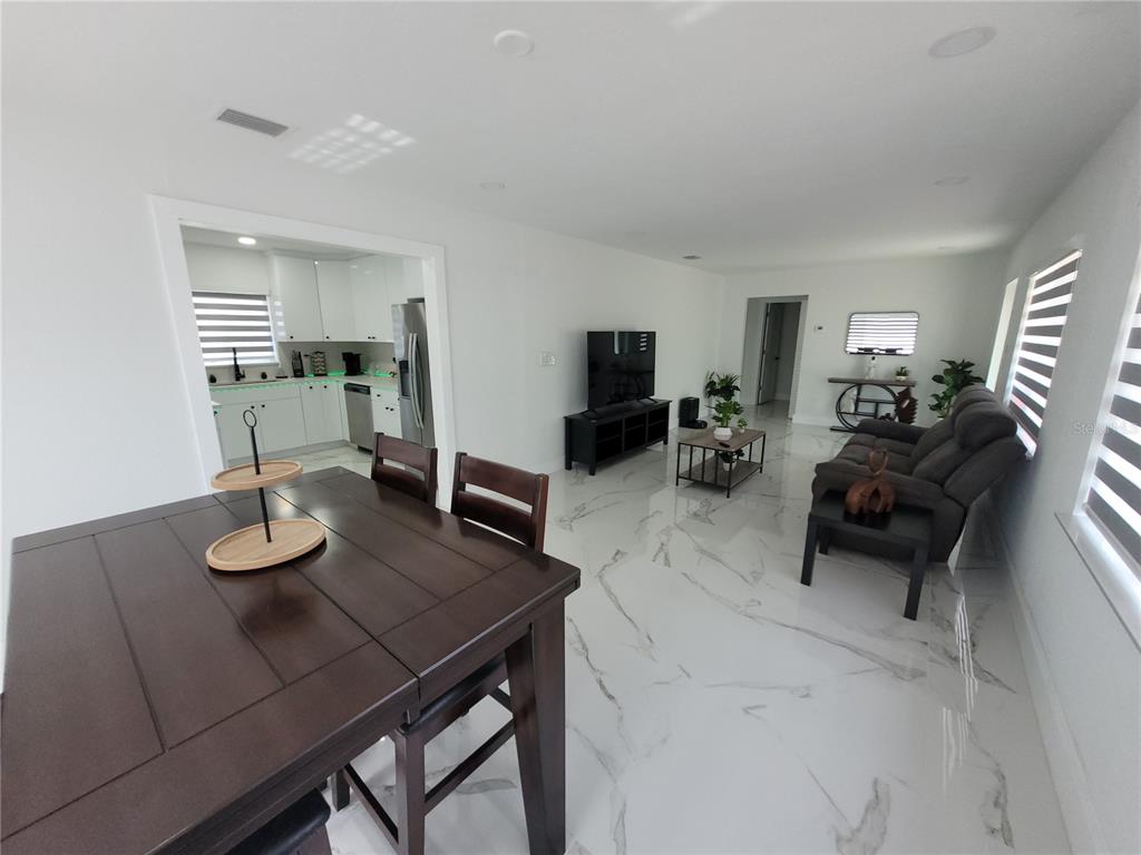 An open-concept living and dining area features white marble-look tile floors and dark wood furniture — 105 FOREST PARK AVENUE, TEMPLE TERRACE, FL