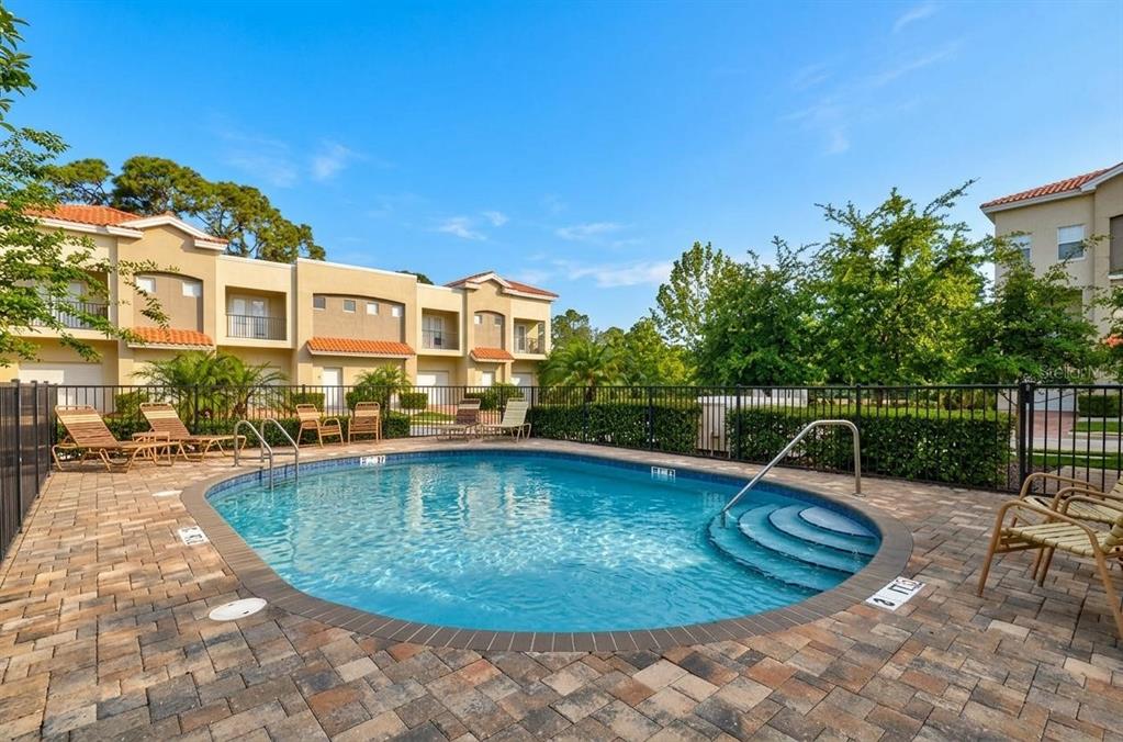 A community swimming pool with lounge chairs on a paved deck in front of townhomes — 501 100TH AVENUE N, ST PETERSBURG, FL