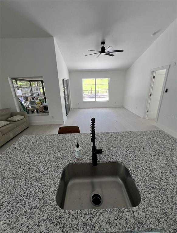 A kitchen island with a granite countertop and sink overlooks an open-concept living area — 12824 DUNHILL DRIVE, TAMPA, FL