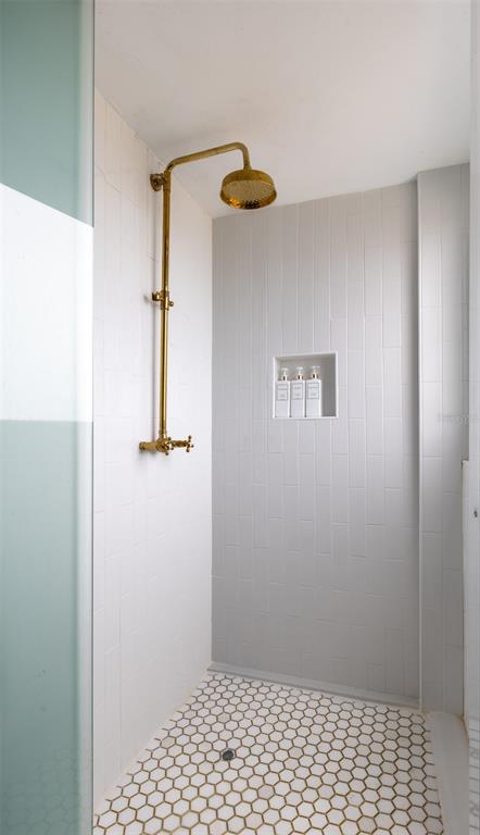 A shower stall features white subway wall tiles, a gold rainfall showerhead, and hexagonal floor tiles — 9 CALLE DEL MERCADO, SAN JUAN, PR