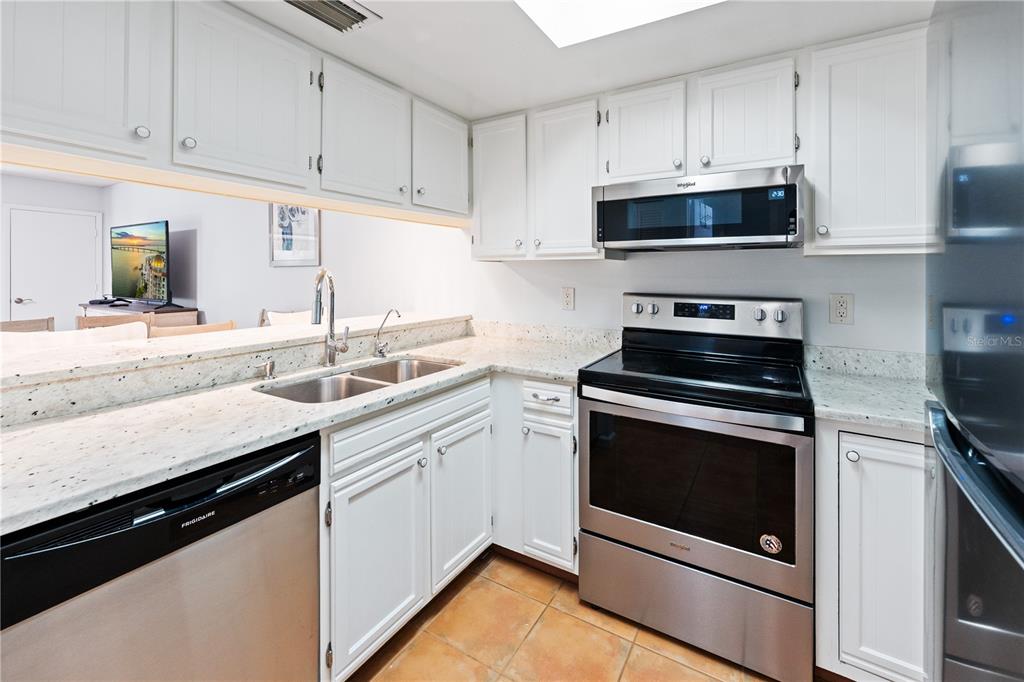 A kitchen with white cabinets, stainless steel appliances, and light-colored granite countertops — 4574 RINGWOOD MEADOW UNIT 4, SARASOTA, FL
