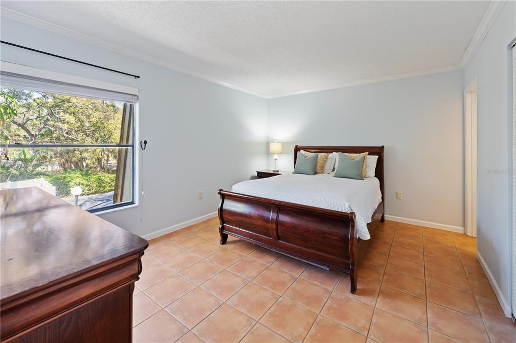 A bedroom features a dark wood sleigh bed, tile flooring, and a large window — 4574 RINGWOOD MEADOW UNIT 4, SARASOTA, FL