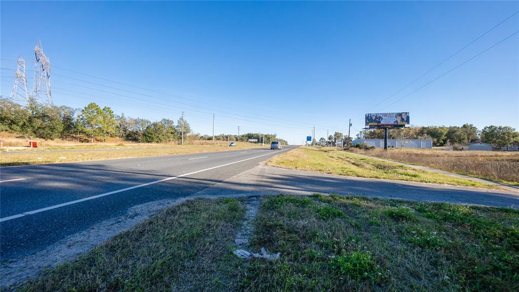A paved road stretches into the distance past a billboard and power lines — 4164 W GULF TO LAKE HIGHWAY, LECANTO, FL