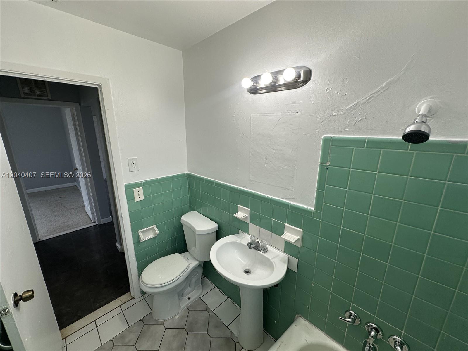 A bathroom features a pedestal sink, a toilet, and green wall tiles — 820 NW 4th Ave, Fort Lauderdale FL 33311, FORT LAUDERDALE, FL