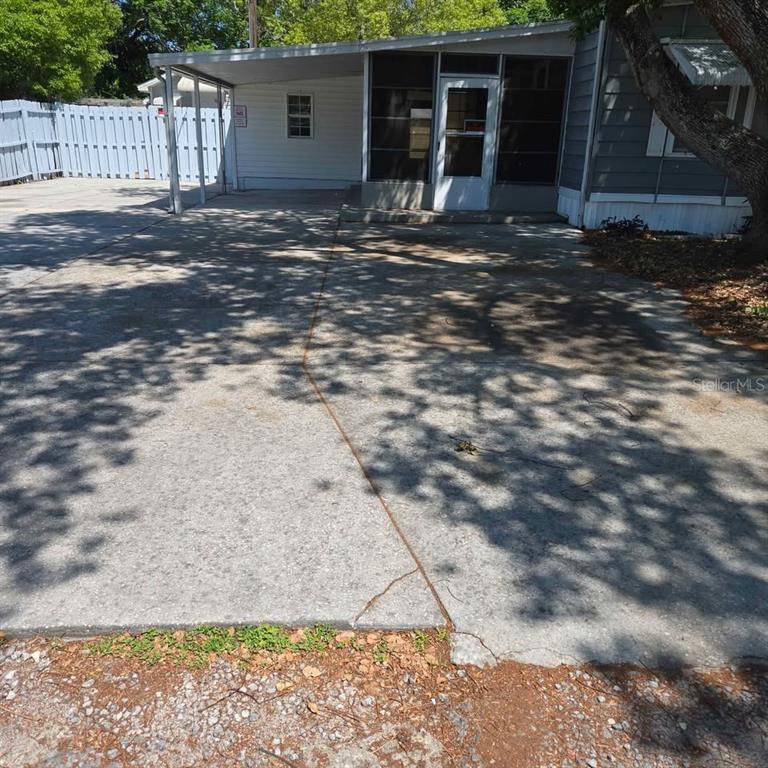 A concrete driveway leads to a covered carport and a screened-in porch of a house — 4030 PECAN DRIVE, NEW PORT RICHEY, FL