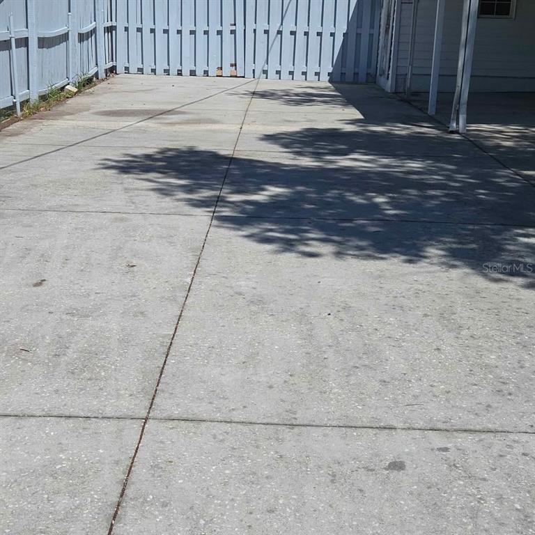 A concrete driveway leads to a light blue wooden fence next to a house — 4030 PECAN DRIVE, NEW PORT RICHEY, FL