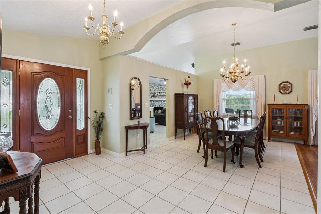 A dining area and entryway feature tile floors, chandeliers, and a wooden front door — 2624 TUSCARORA TRAIL, MAITLAND, FL