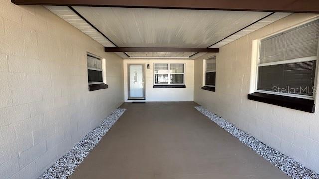 A covered carport with a concrete floor, beige block walls, and a white ceiling — 4407 N SUWANEE AVENUE, TAMPA, FL