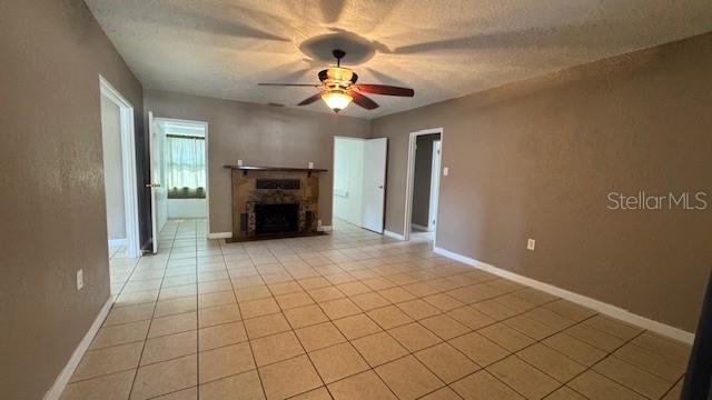 A living room with beige tile floors, a stone fireplace, and a ceiling fan — 4407 N SUWANEE AVENUE, TAMPA, FL