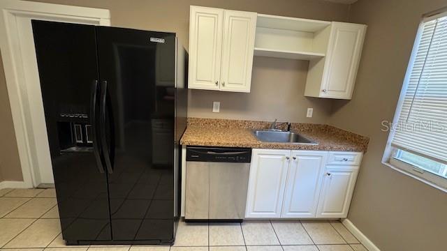 A kitchen features a black refrigerator, white cabinets, a stainless steel dishwasher, and granite countertops — 4407 N SUWANEE AVENUE, TAMPA, FL