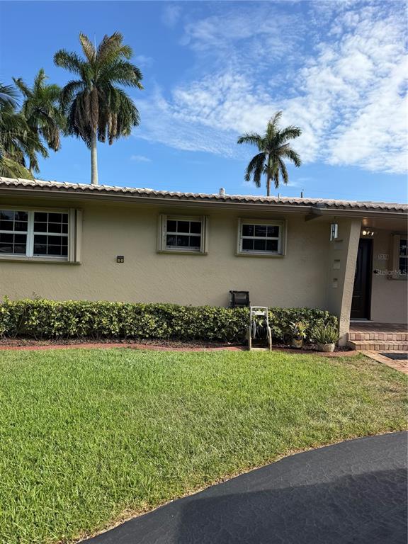 The exterior of a tan house features a green hedge, palm trees, and a driveway — 3230 HARRISON STREET, HOLLYWOOD, FL