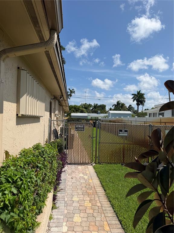 A paved walkway leads to a gated side yard with a beware of dog sign — 3230 HARRISON STREET, HOLLYWOOD, FL