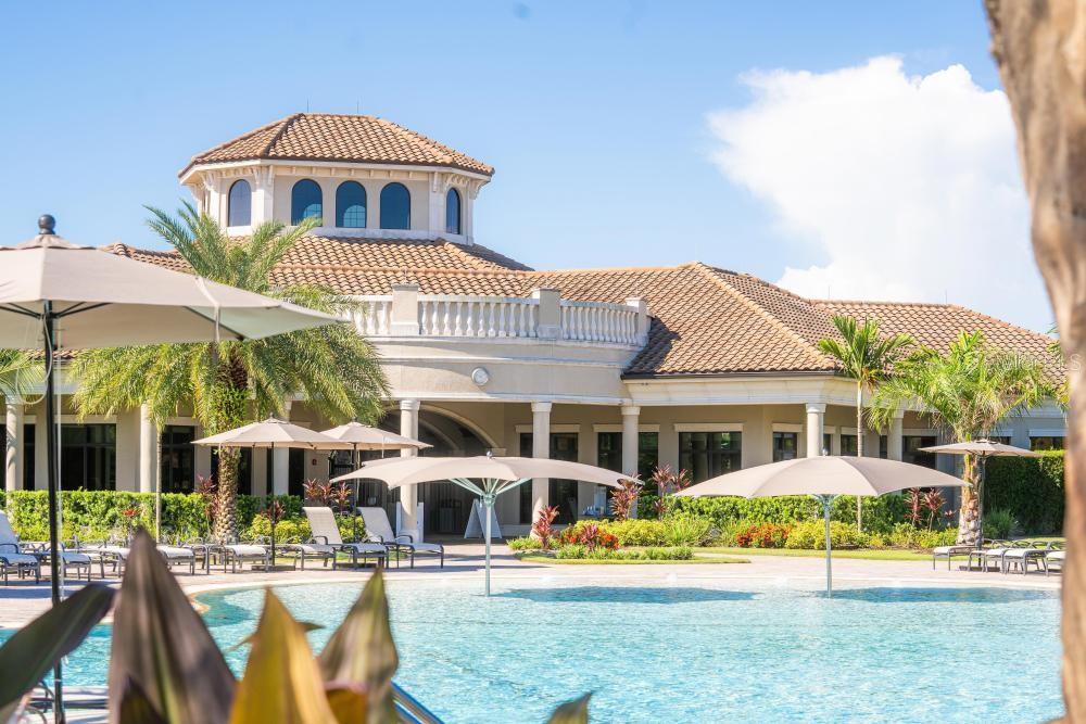 A swimming pool with umbrellas sits in front of a large building with a cupola — 17724 GAWTHROP DRIVE UNIT 208, BRADENTON, FL